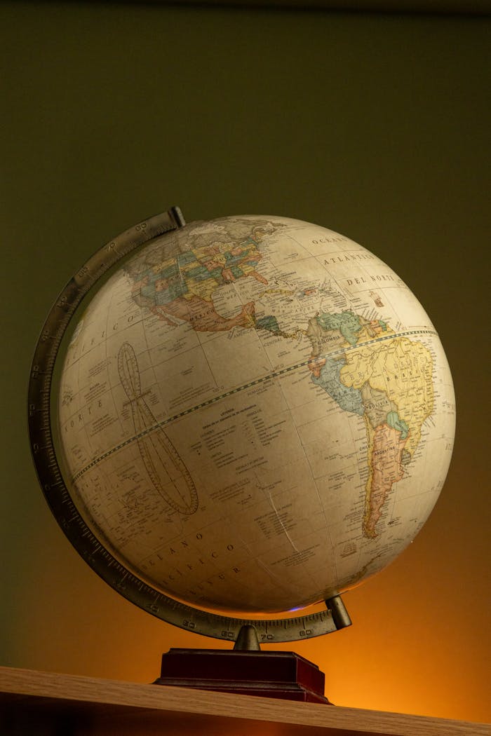 A classic globe depicting North and South America, warmly lit on a wooden base.